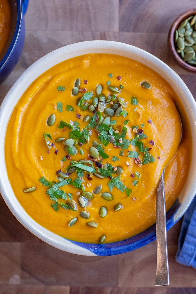 bowl of roasted root vegetable soup with a spoon and blue napkin