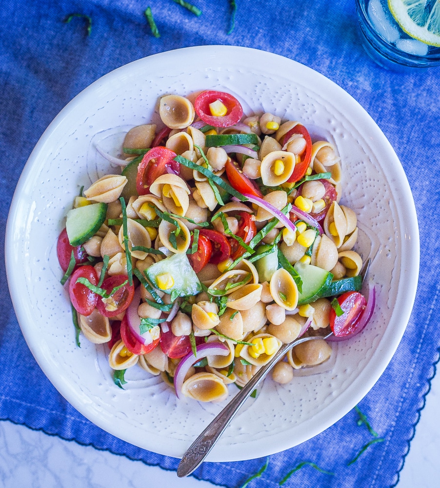 Bowl of summer vegetable pasta salad on a blue tablecloth