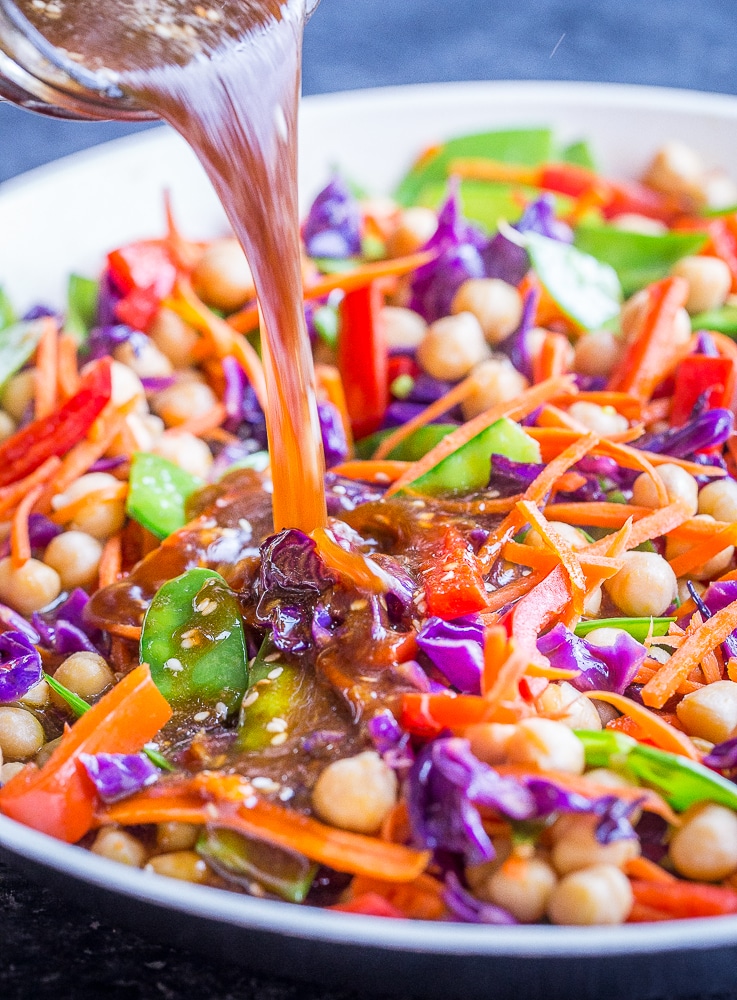 Pouring the best stir fry sauce over a pan of vegetables