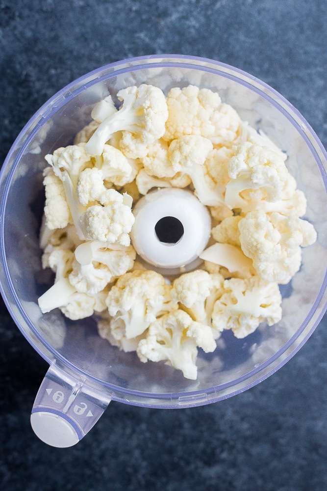 Food processor full of cauliflower florets for how to make cauliflower rice