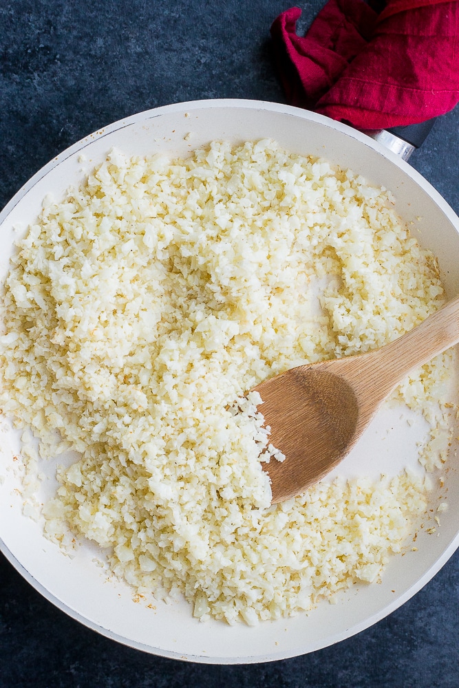Pan of cauliflower rice with a wooden spoon in it