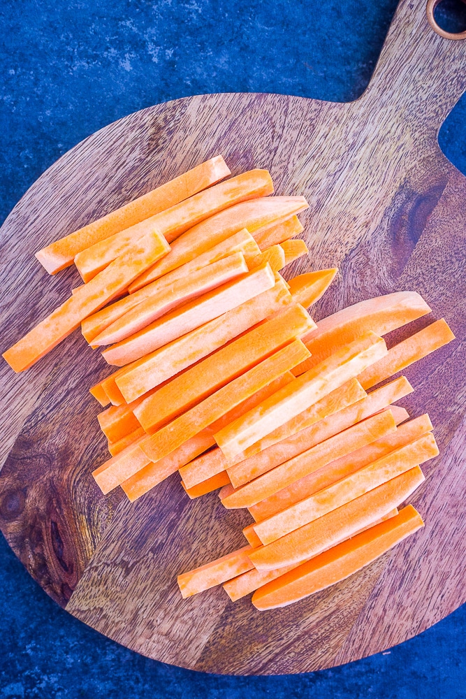 Sweet Potato cut in fry shapes on a cutting board for baked sweet potato fries