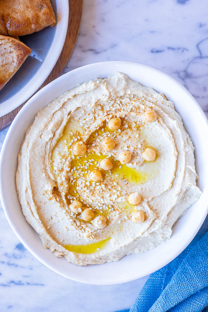 The creamiest hummus recipe in a. bowl with pita bread