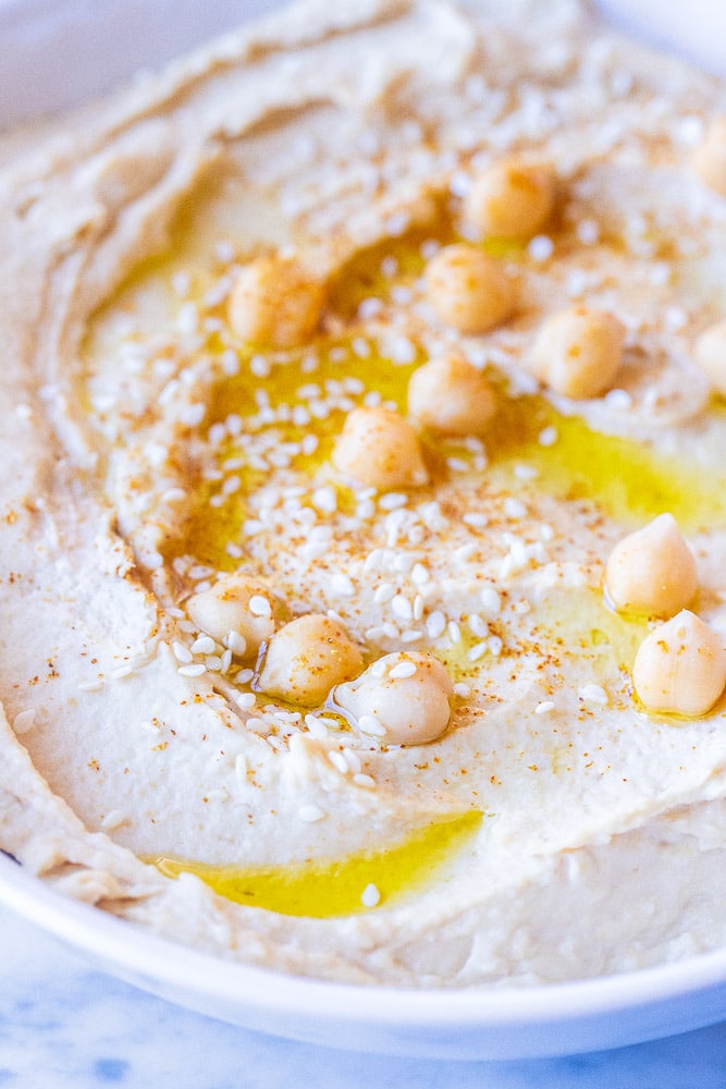 A close up of a bowl of creamy hummus