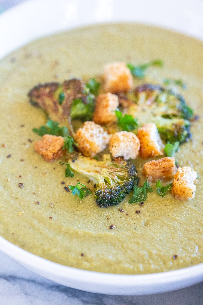 close up of roasted broccoli soup in a bowl with croutons