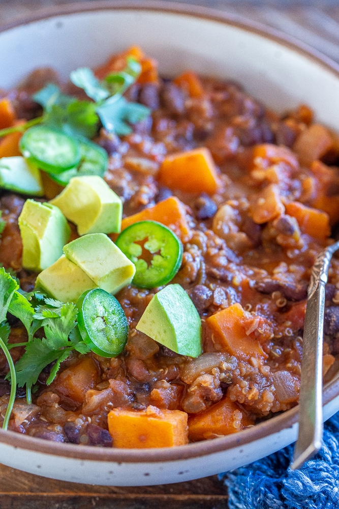 close up of sweet potato and quinoa chili in a bowl with avocado