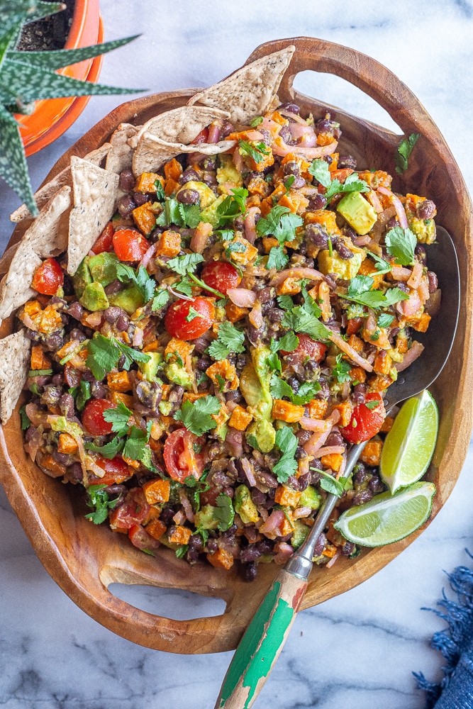 roasted sweet potato salad in a large wooden bowl with a spoon and chips
