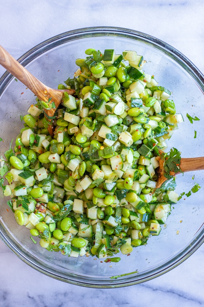 cucumber edamame salad mixed together in a glass bowl