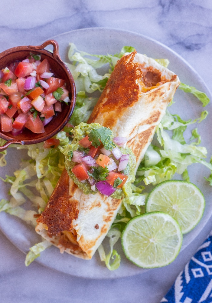 crispy rolled bean and cheese burrito on a plate with lettuce and salsa