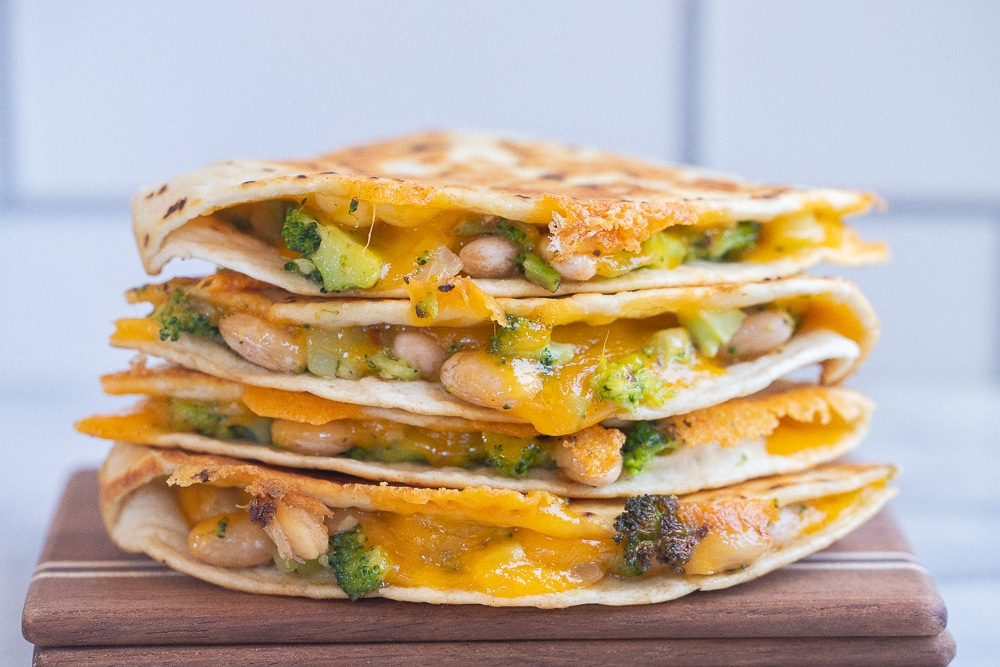 close up of broccoli cheddar white bean quesadillas on a cutting board
