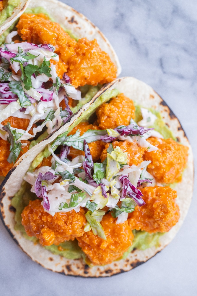 close up of crispy buffalo tofu tacos with slaw and guacamole