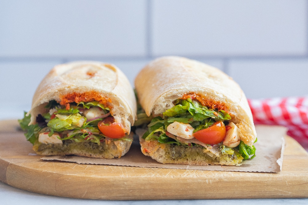 two caprese salad sandwiches on a cutting board next to each other