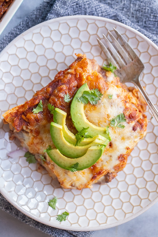 close up of a slice of bean and cheese enchilada casserole on a plate