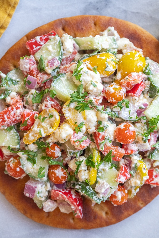 close up of a creamy feta and veggie pita topped with fresh herbs