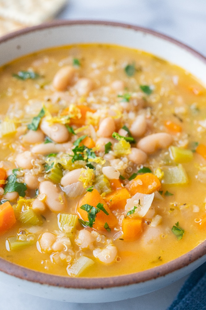 close up of a bowl of lemon white bean soup with carrots and celery