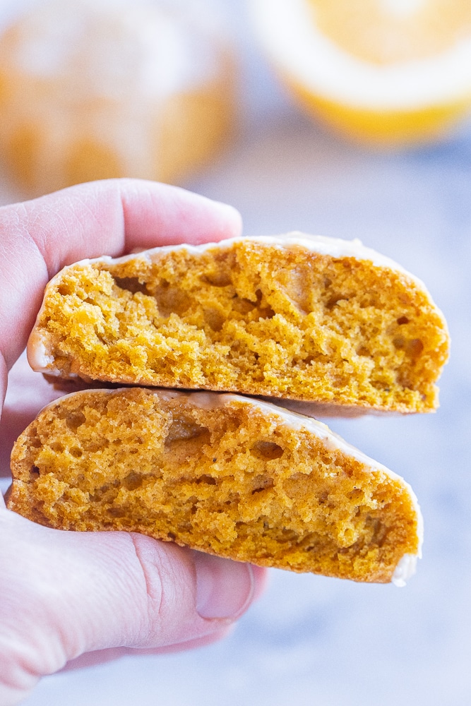 a hand holding a pumpkin cookie that has been broken in half