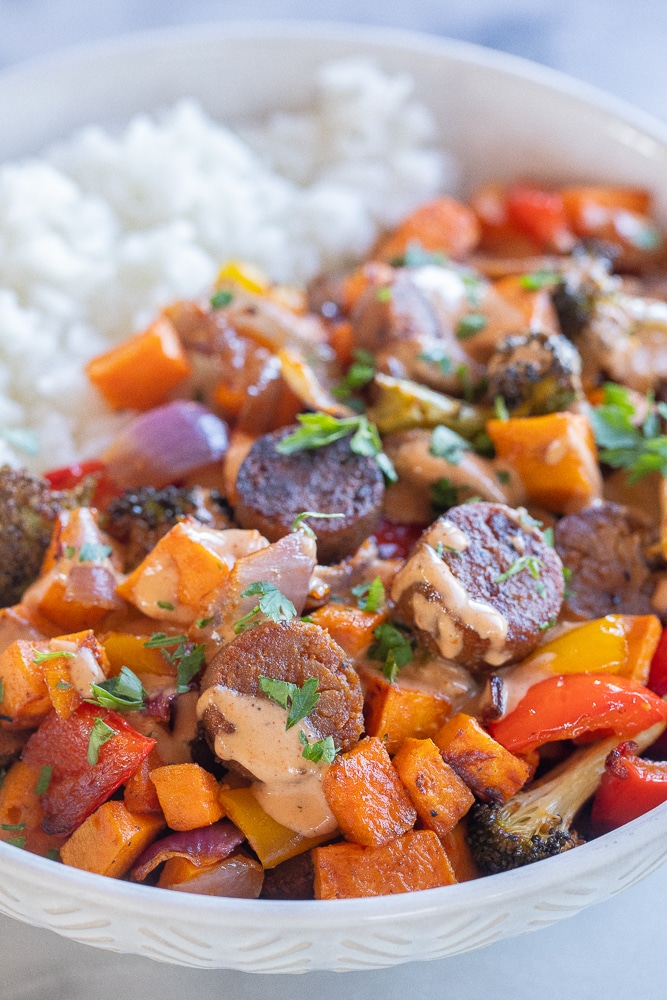 close up of a vegan sheet pan dinner over rice with tahini dressing