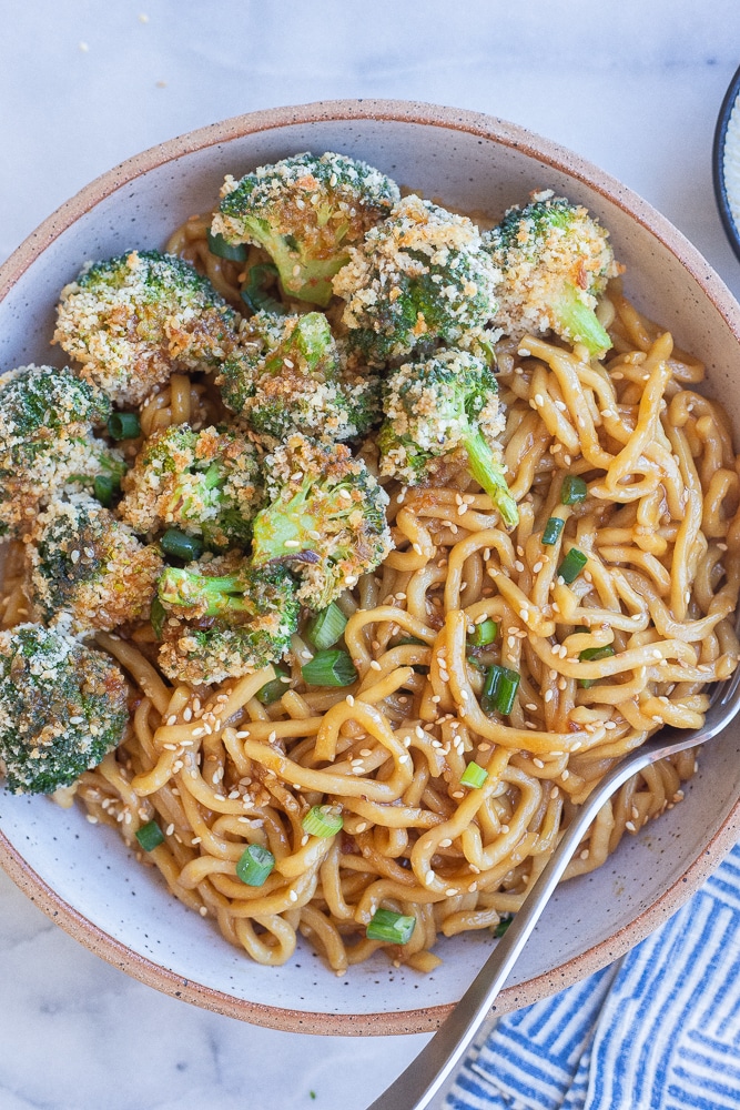 bowl of teriyaki noodles with a side of crispy baked broccoli