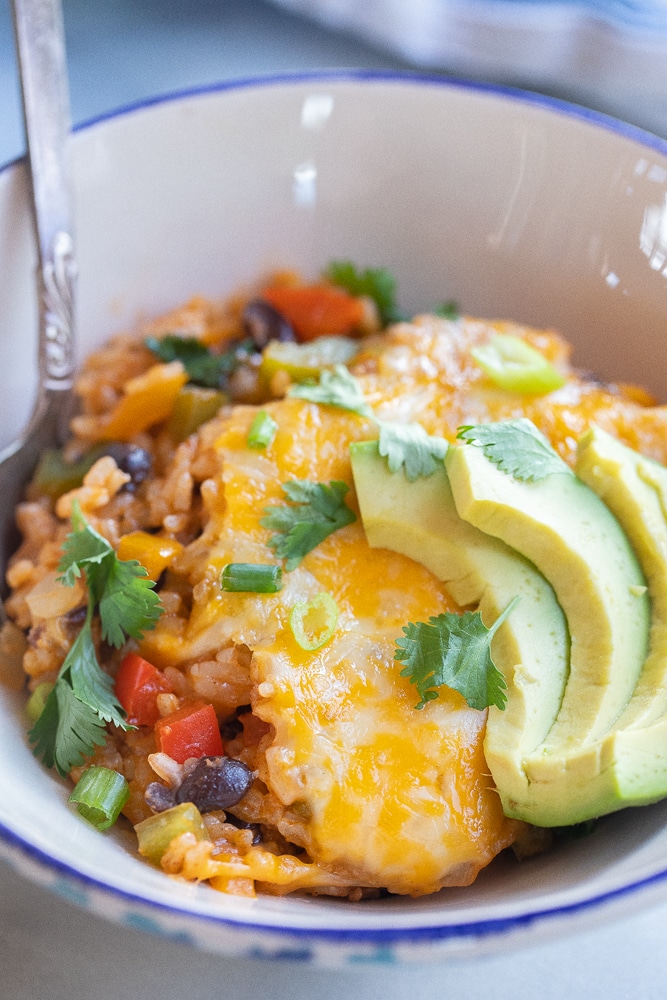 close up of a bowl of fajita rice casserole with avocado