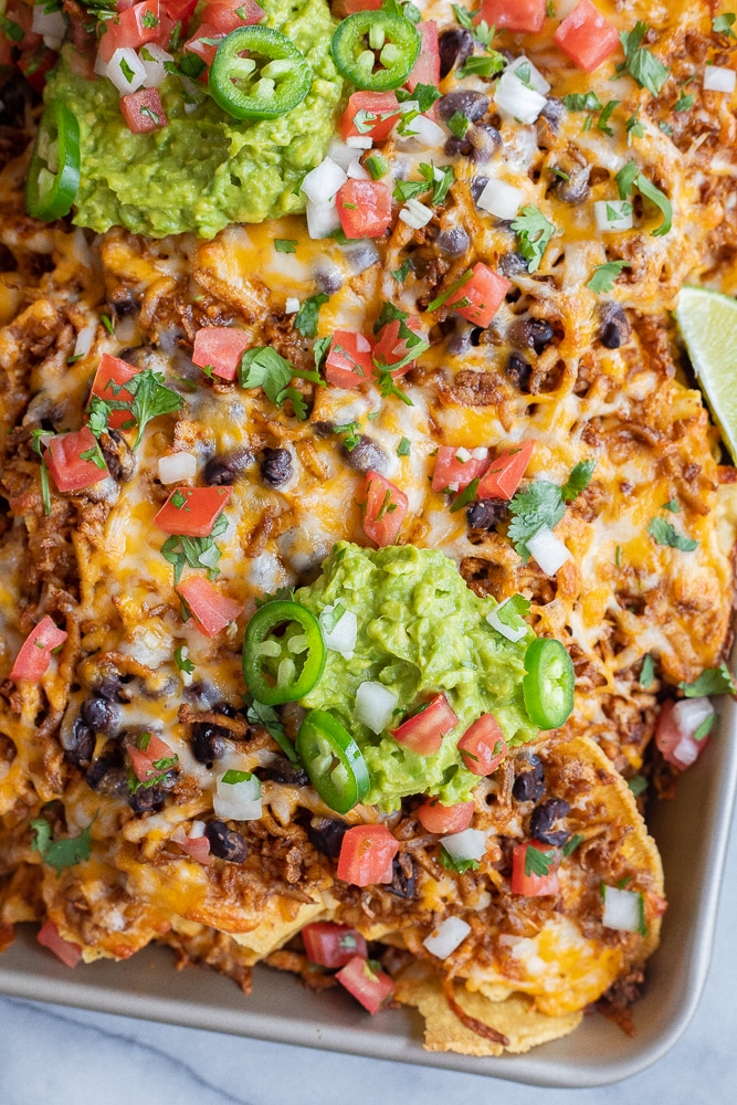 pan of vegetarian shredded tofu nachos with guacamole and pico de gallo