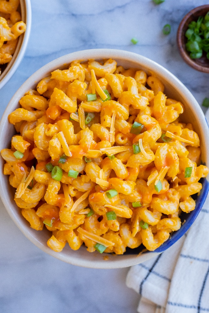 large bowl full of cheesy buffalo butternut squash pasta topped with sliced scallions