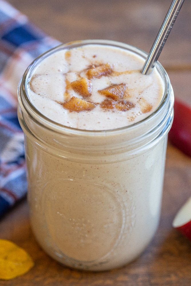 mason jar full of a caramelized apple smoothie with caramel drizzled on top