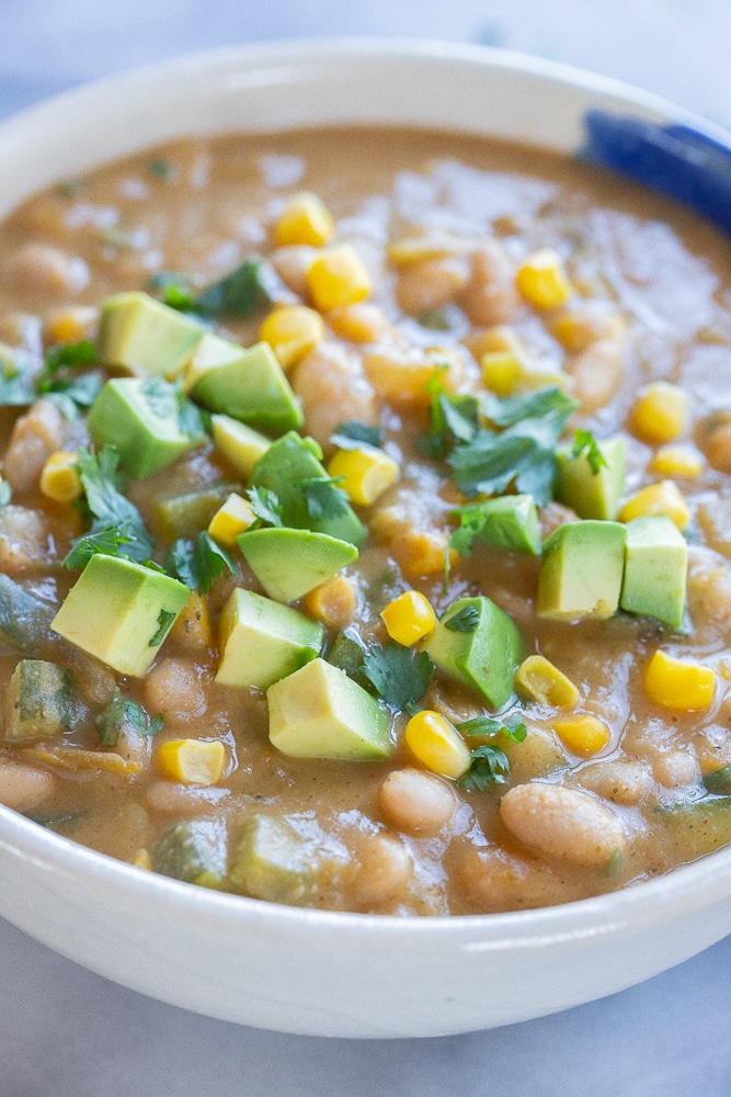 close up of a bowl of vegan white bean chili with zucchini and corn