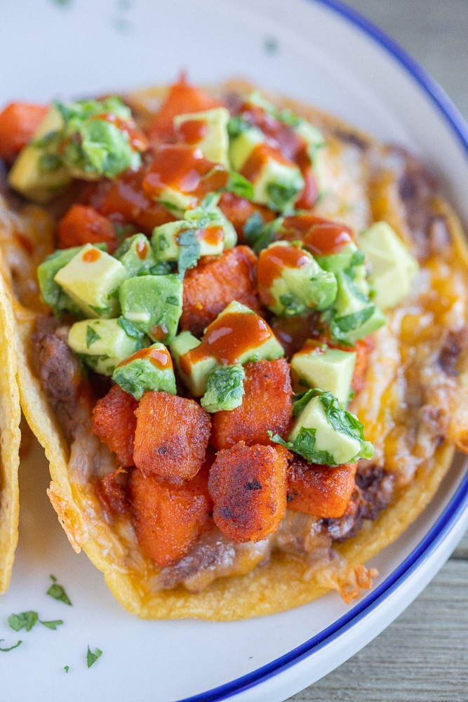 close up of crispy seasoned sweet potatoes in a taco topped with avocado