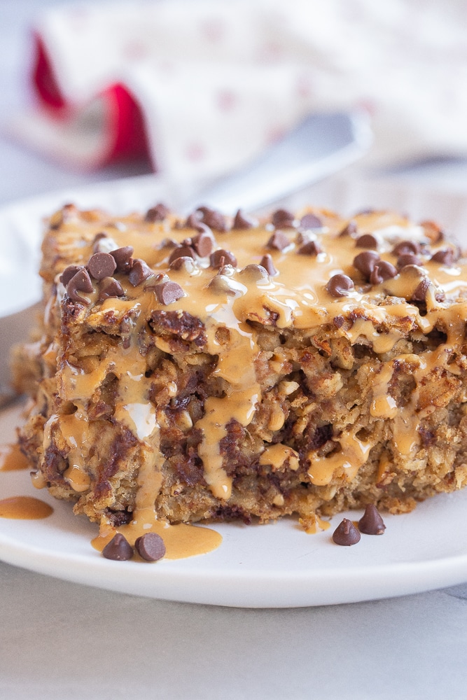 close up of a slice of high protein baked oatmeal topped with peanut butter and chocolate chips