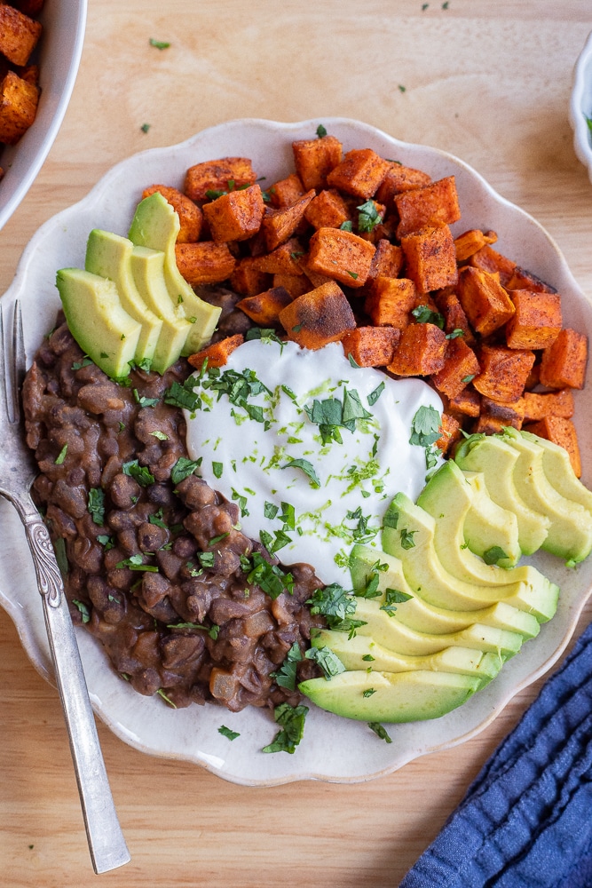 bowl of cottage cheese sweet potato and black beans topped with fresh cilantro and avocado