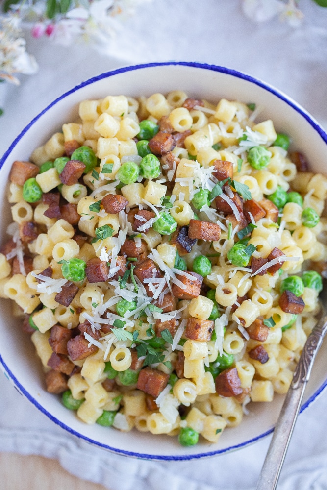 bowl of vegetarian pasta with peas and pancetta with cherry blossoms