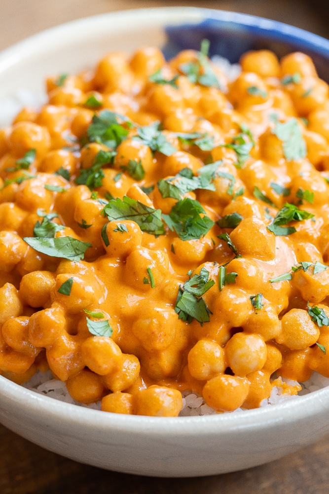 close up of a bowl of red curry chickpeas with chopped cilantro
