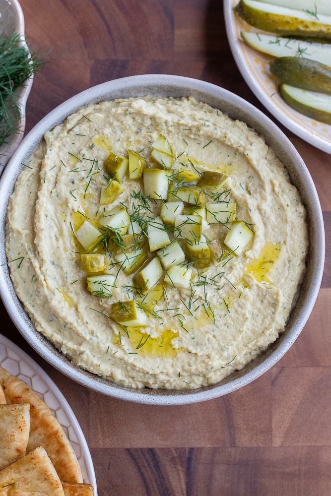 This tangy Dill Pickle Hummus is easy to make and great to have on hand during the summer, for a refreshing and healthy snack. The food processor does most of the work and this unique hummus can be used in so many different ways. Mix it into pasta salad, spread it on sandwiches or enjoy it in salads. If you love dill pickles, you've got to make this delicious hummus recipe. #hummus #dillpickle #diprecipe #snack #vegan