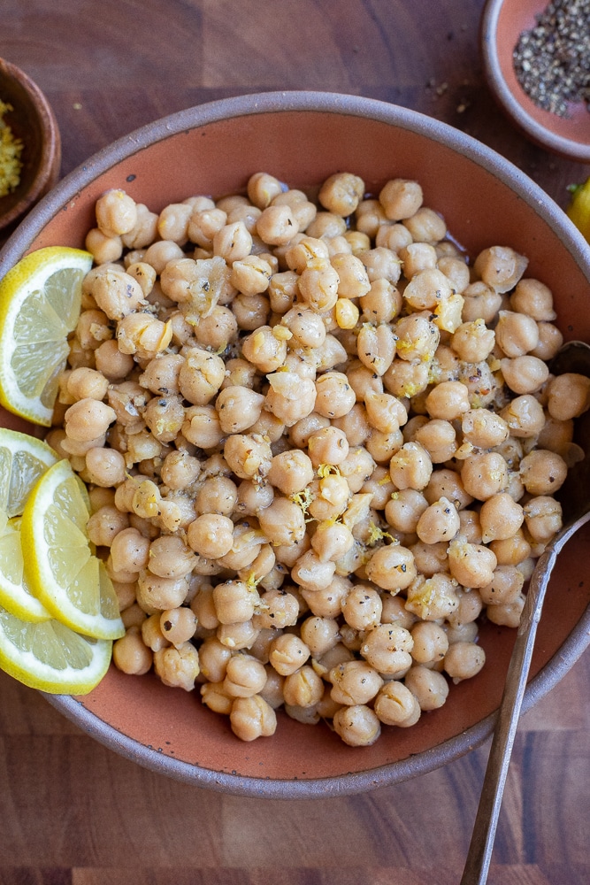 lemon pepper marinated chickpeas in a bowl with lemon slices