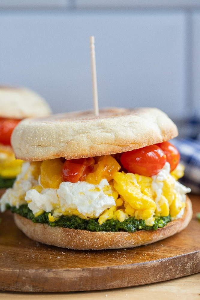 close up of a tomato goat cheese and kale pesto breakfast sandwiches on a cutting board