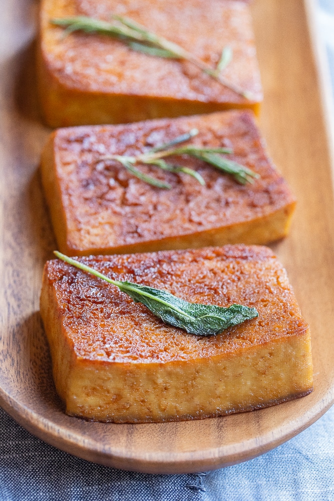 close up of a garlic herb butter tofu steak on a wooden serving platter