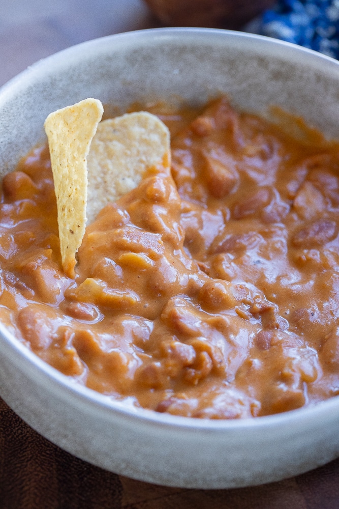 Bowl of cheesy beans with a tortilla chip