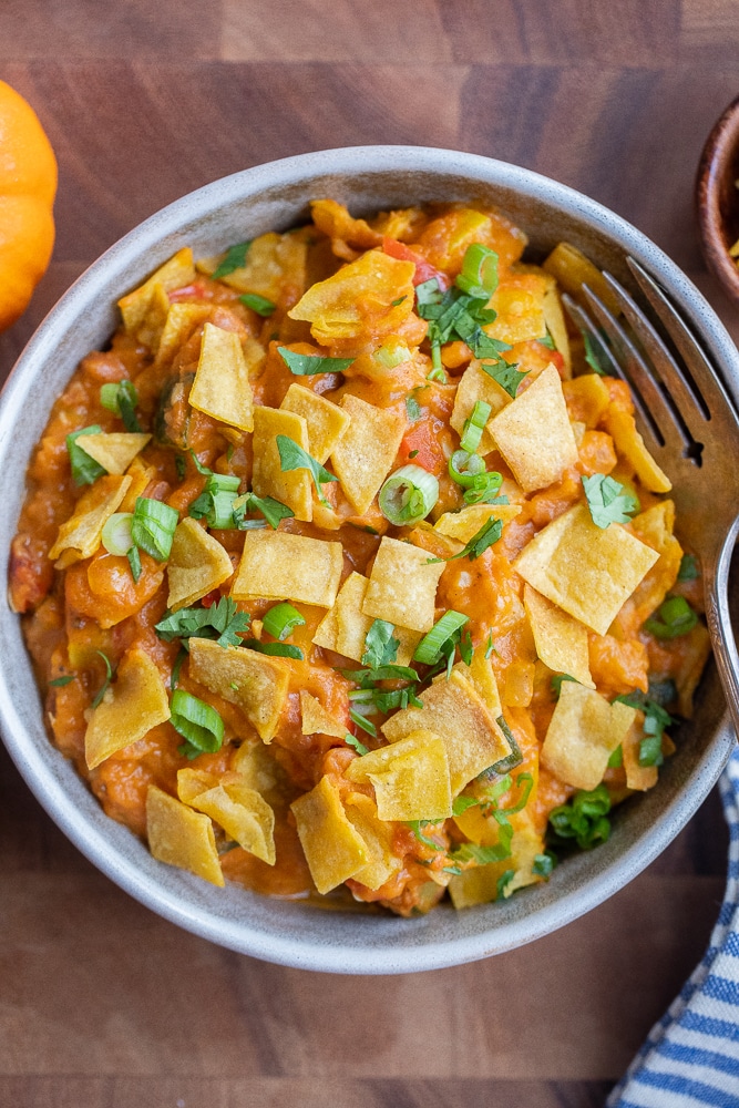 pumpkin pinto bean taco skillet in a bowl topped with crispy corn tortillas