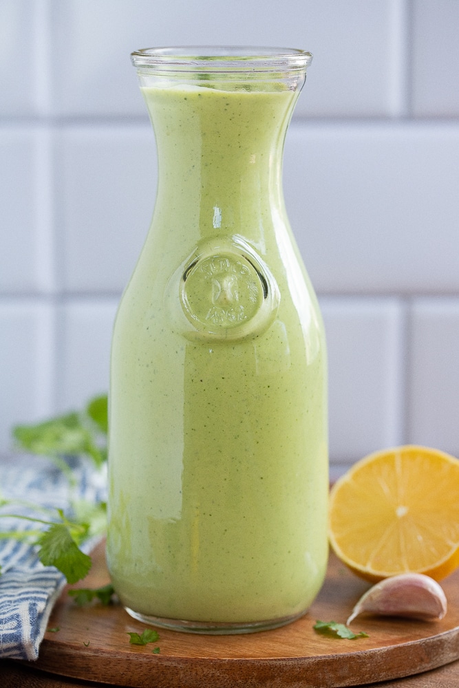 Herbed yogurt dressing in a jar on cutting board