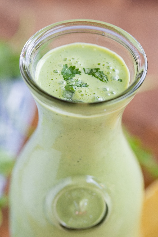 close up of green herbed yogurt dressing in a glass serving jar