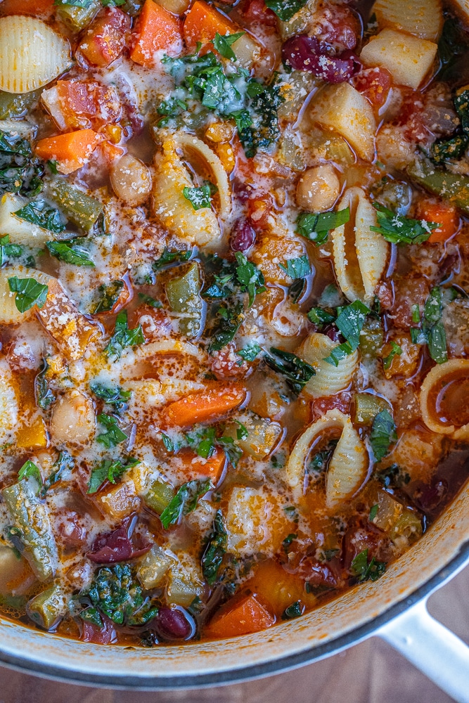 close up of minestrone soup in a pot topped with parmesan cheese