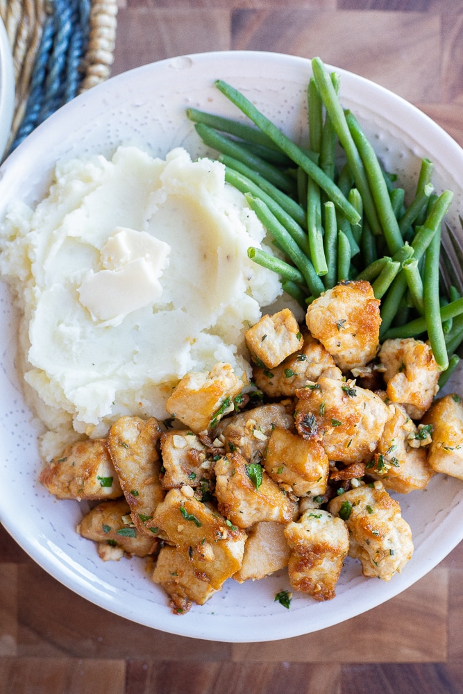 crispy garlic tofu in a bowl with mashed potatoes and green beans