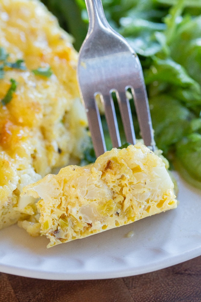 close up of a slice of cauliflower leek egg bake with white cheddar cheese
