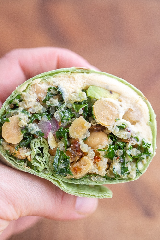 close up of a hand holding a vegetarian superfood wrap that has been cut in half