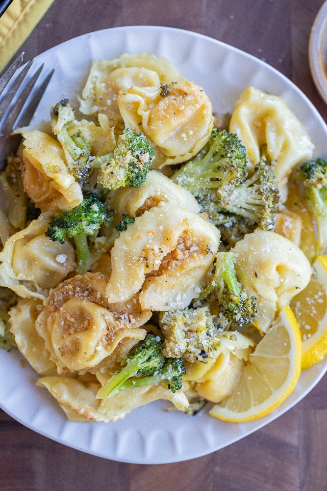 close up of a plate of roasted tortellini with broccoli topped with parmesan